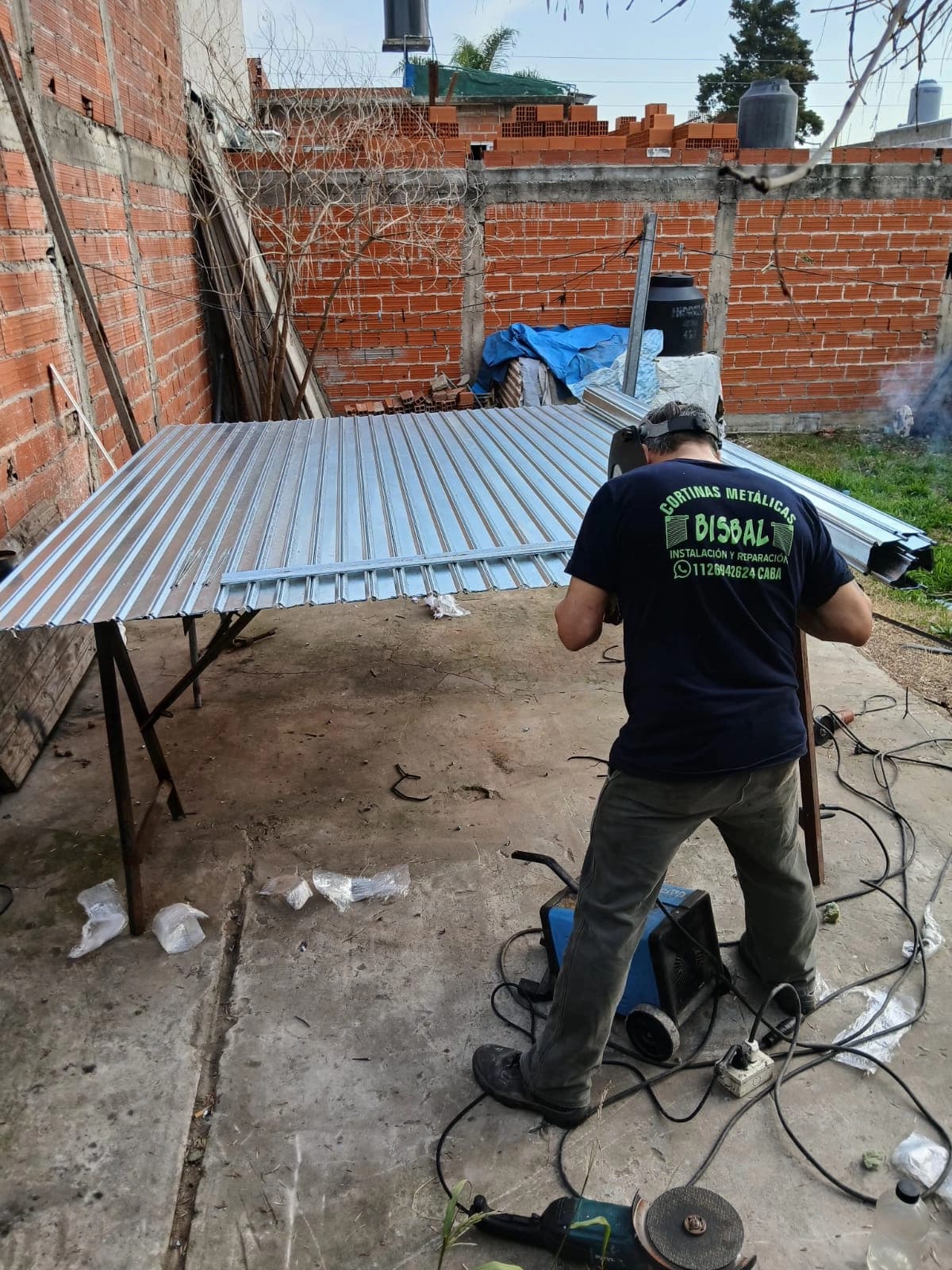 Figura de un señor trabajando en la instalación de una cortina metálica