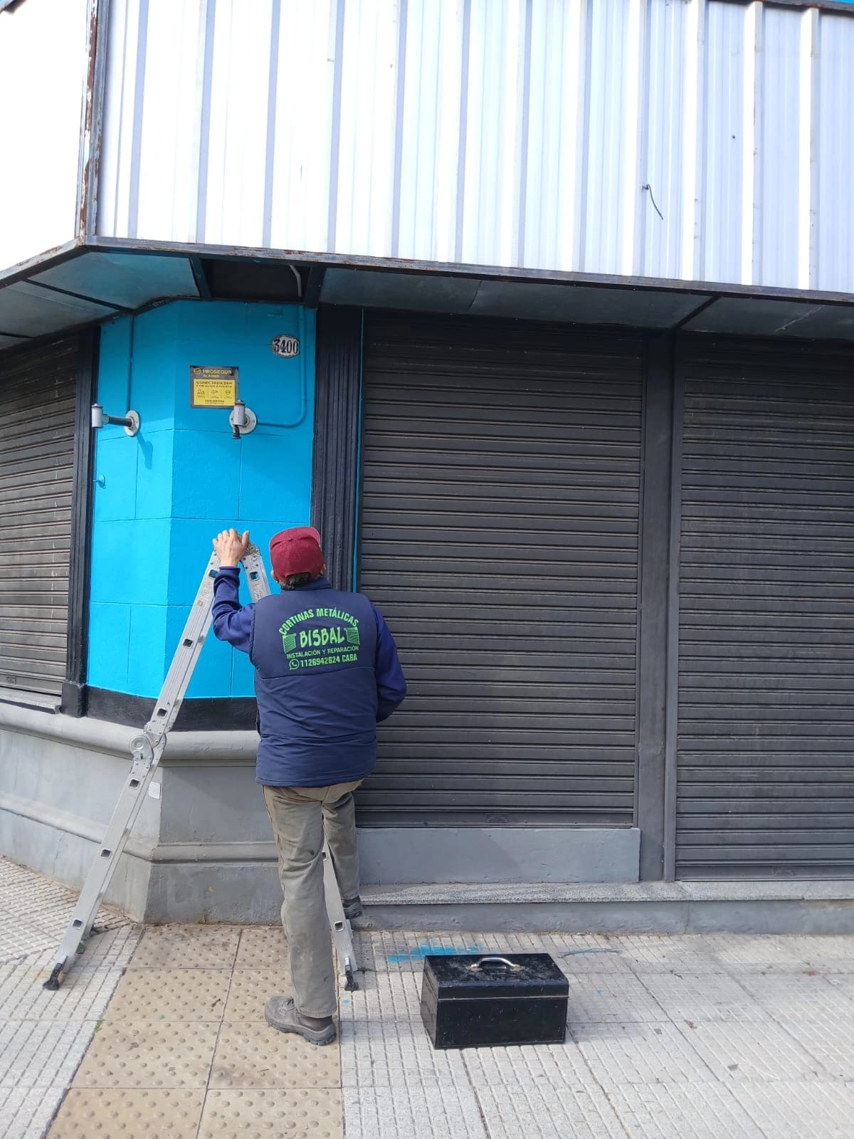 Persona trabajando en la instalación de una cortina metálica