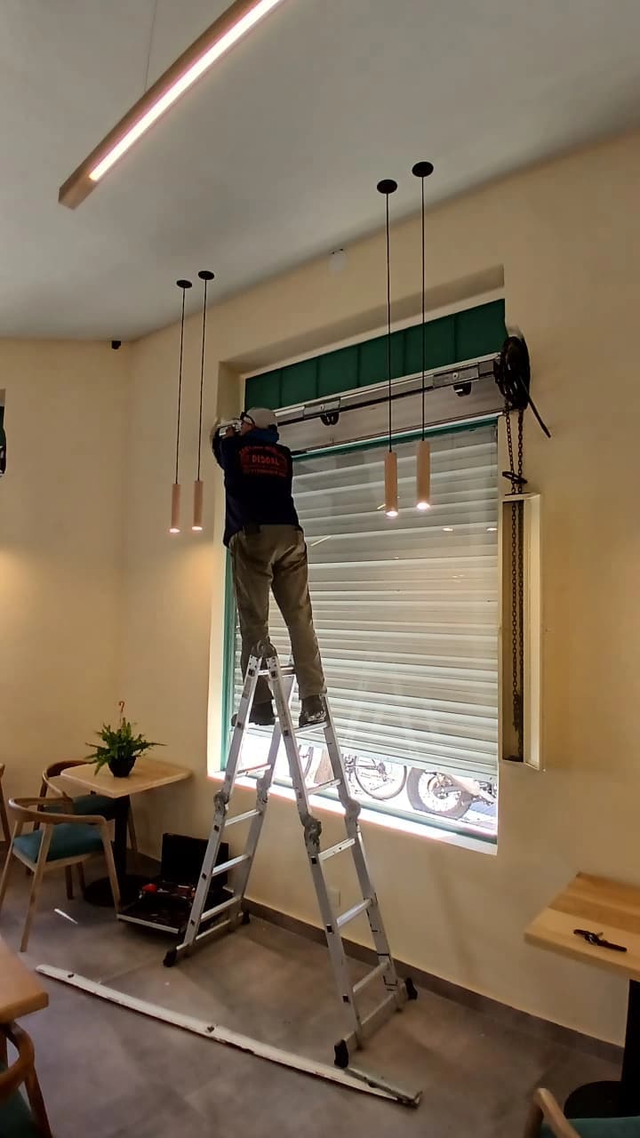 Un señor instalando una persiana automática en un local